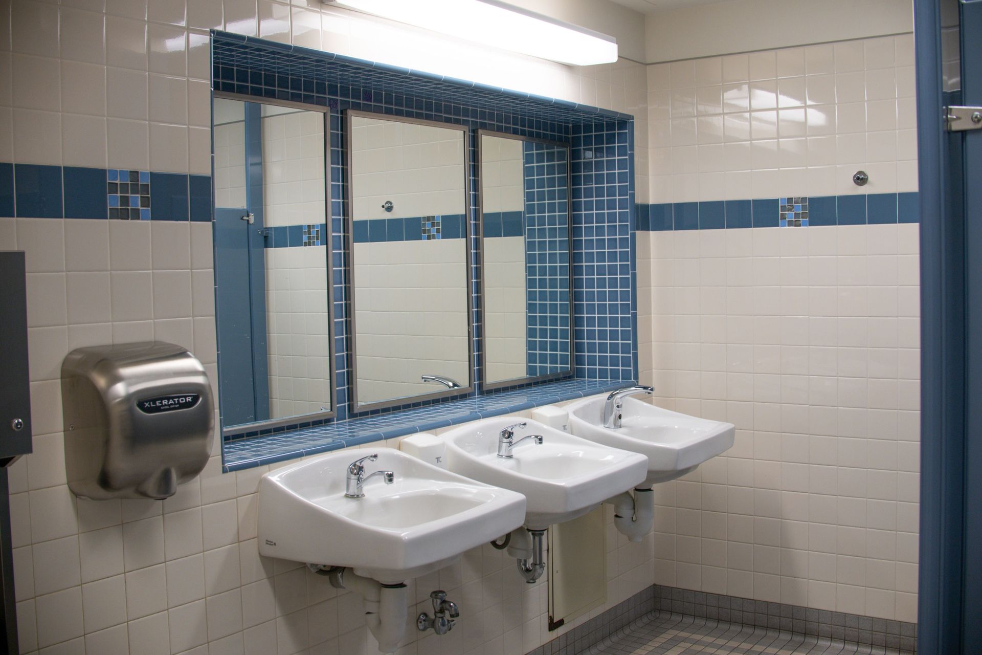 Clean and bright public bathroom with sinks, mirrors, and a hand dryer.
